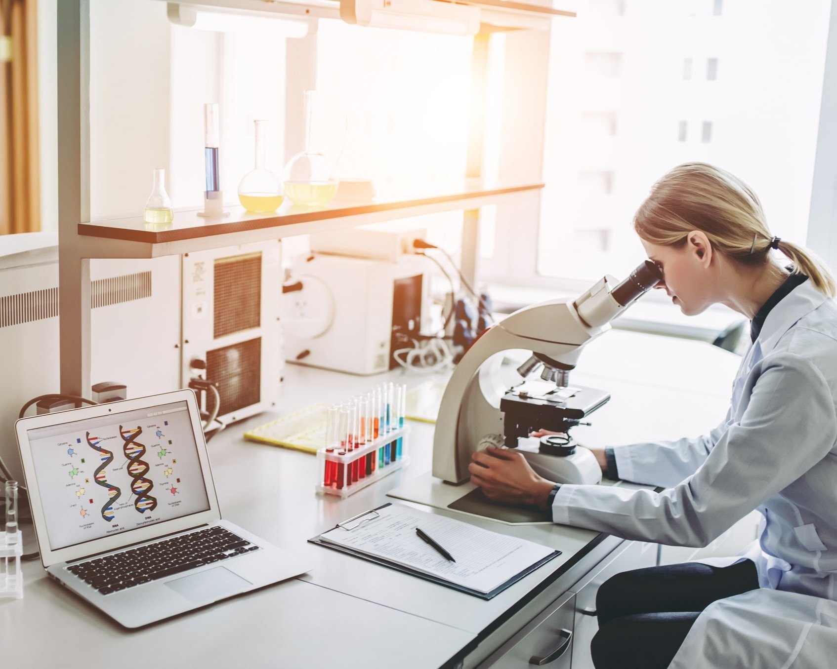 Two scientists working in laboratory. Young female researcher and her senior supervisor are doing investigations on laboratory equipment.
